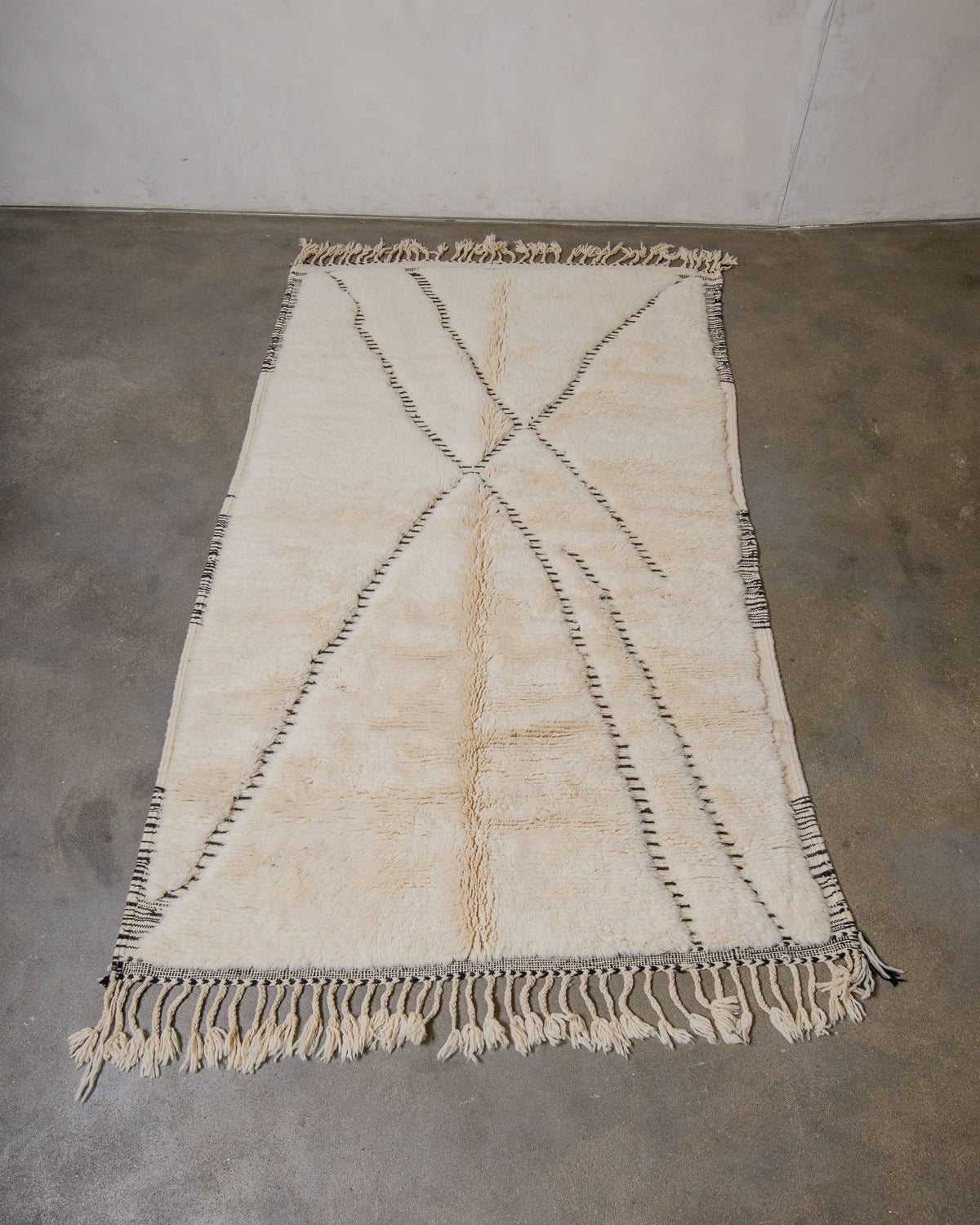 Cream wool rug with black design on concrete floor